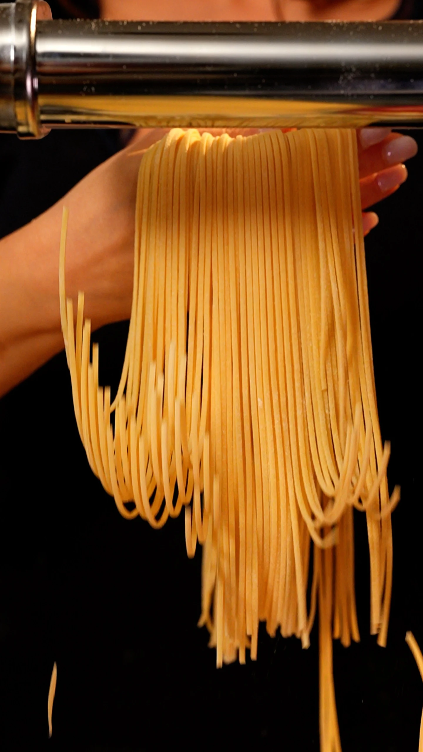 Fresh pasta being rolled through a pasta machine